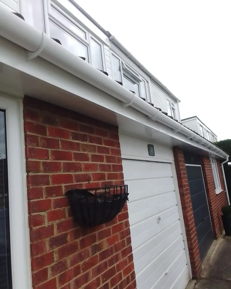 White fascias, gutters and windows on the side of a brick house